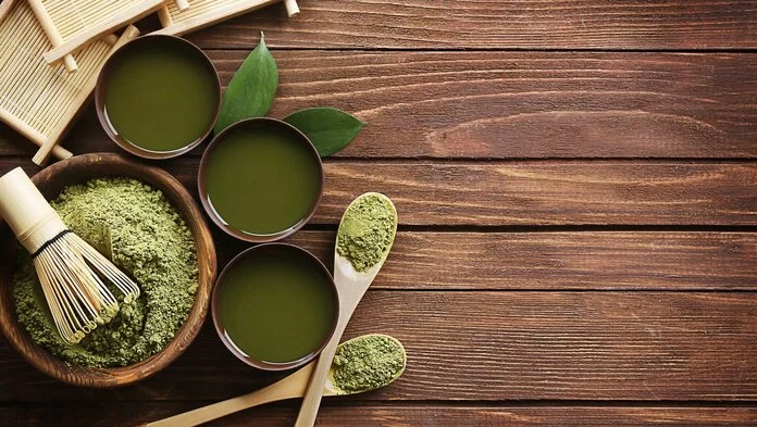 Matcha-Tee, © Pixabay, dungthuyvunguyen Drei Schalen mit Matcha-Tee und eine Schale mit grünem Matcha-Pulver und einem Bambusbesen sowie zwei Löffel, angerichtet auf einer Holzunterlage.