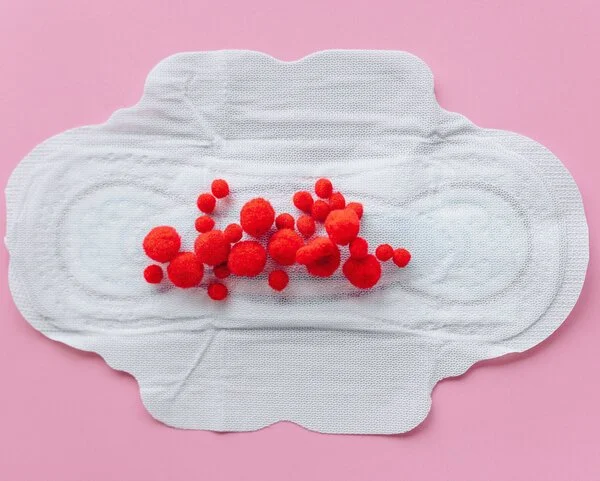 Menstruation, © Nataliya Vaitkevich, Pexels Symbolisches Bild von Monatsbinde mit Stoffbällchen als Blut.