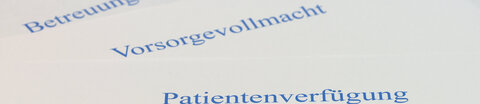 Auf einem Tisch liegen eine Patientenverfügung, eine Vorsorgevollmacht und eine Betreuungsverfügung, darauf liegt ein Stift.