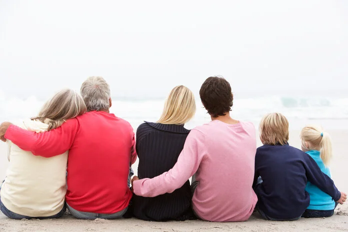 Familie am Strand, © Monkey Business Images, Shutterstock Familie aus drei Generationen sitzt am Strand