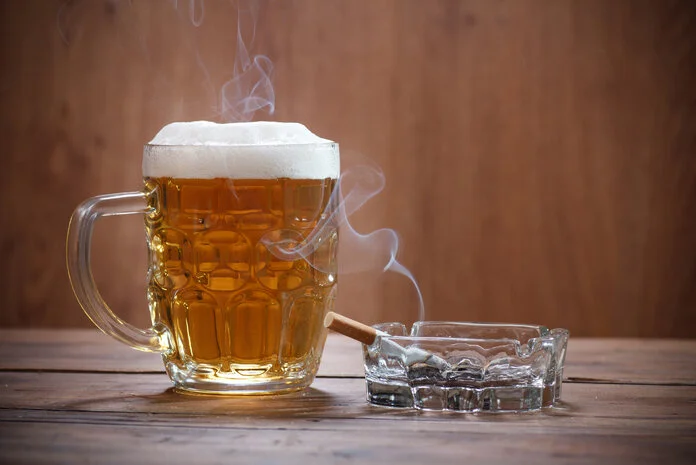 Alkohol und Tabak, © Lecic - thinkstock.com Volles Bierglas steht auf einem Tisch neben einem Aschenbecher mit einer qualmenden Zigarette