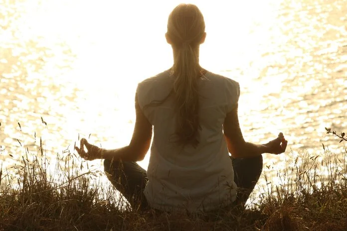 Meditation am See, © Pexels, Pixabay Silhouette einer meditierenden Frau im Schneidersitz am See (Rückenansicht).