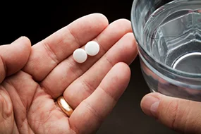 Frau hält Tabletten und Wasserglas in der Hand Frau hält Tabletten und Wasserglas in der Hand © leventince - Getty Images