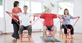 Körperliches Training ist Teil der Reha nach Lungenkrebs. Drei Patienten machen unter Anleitung einer Physiotherapeutin Gymnastik mit einem Fitnessband. © Christopher Pattberg, Thinkstock